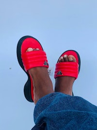 the feet of a person wearing red and black sandals